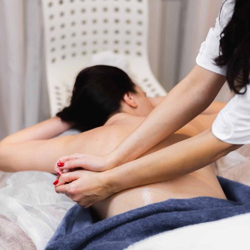 The girl in the spa salon receives a back and neck massage, lies in the cosmetology table, relaxed and enjoys the process